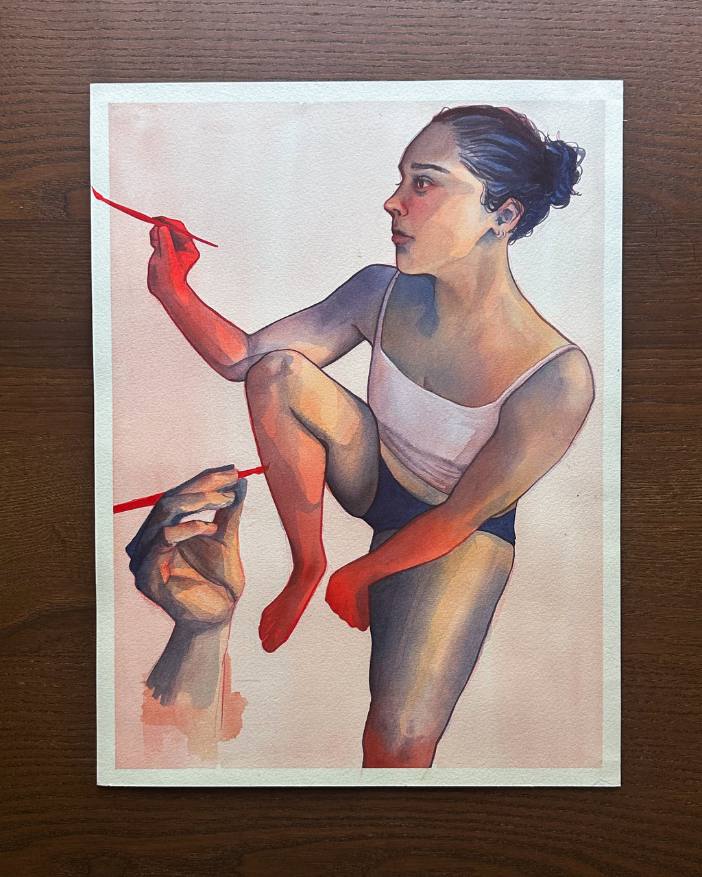 Artistic depiction of a person with red paintbrushes and bright red limbs. Watercolor painting on a wooden surface.